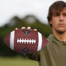 Brown football with white laces and white stripe, held in hands