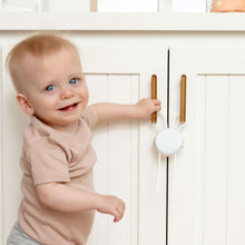 Childproof cabinet strap lock installed with white round base and brown bars