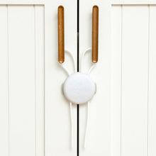 Baby proof cabinet strap lock with white round release and brown anchor bars