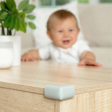 Light grey corner safety cushion secured to a wooden furniture corner