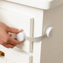 Hand pressing a white child safety latch cover on a cabinet door