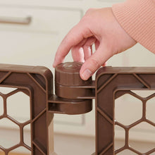 Hands securing the brown play yard door latch into the gate frame