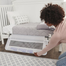 Regalo swing-down crib rail with mesh barrier being secured to the mattress