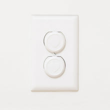 White double outlet safety plug with two round covers on a wall plate