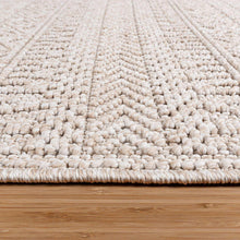 Light beige area rug with textured looped pile and braided border