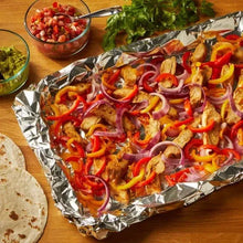 Aluminum foil-lined roasting tray with sliced peppers, onions, and cooked meat