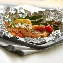 Aluminum foil-lined roasting tray with herb-seasoned chicken and tomatoes