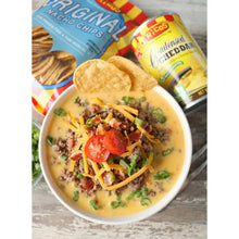 Cheddar cheese sauce in a bowl with toppings and tortilla chips.
