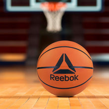 Orange Reebok basketball on indoor court with textured surface and black seams