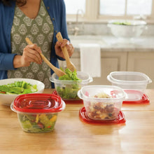 Clear square food storage containers with red lids arranged on a kitchen table.