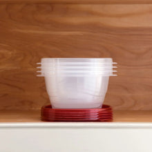 Stacked clear square food storage container with red lid base on a countertop.