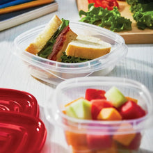 Clear food storage container with red lid, holding sandwich pieces and greens