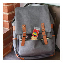 Gray backpack with brown leather straps and a Ritz cracker patch