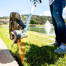 Gas string trimmer cutting grass along a concrete edge, with spray from the guard