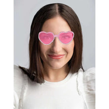 Pink heart sunglasses with rhinestone border, worn on a woman