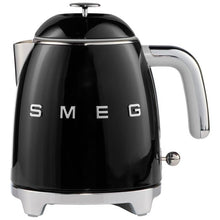 Black mini electric kettle close-up with chrome handle and SMEG logo letters.