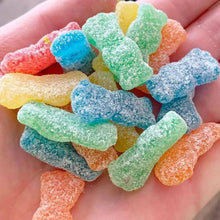Assorted sour candy gummies in bright colors, hand-held close-up