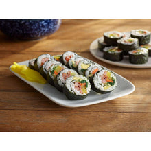 Sushi roll slices with rice, vegetables, and ham on a white plate