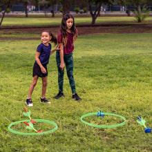 Lawn darts in green rings with blue and red dart pieces on outdoor grass.