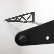 Wall-mounted tire rack with black steel triangular supports and slanted bar