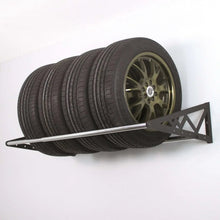 Wall-mounted tire rack holding stacked tires on black metal frame and bar