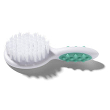 Baby hair brush with soft bristles and teal textured grip pads on white handle