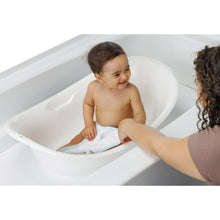 White baby bathtub with child seated and caregiver supporting, interior view