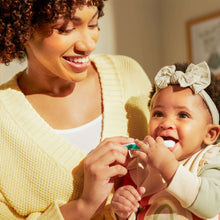 Baby health kit oral-care tool with green handle touching baby’s cheek