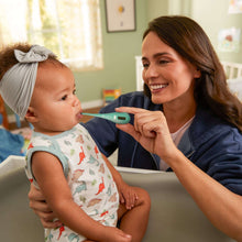 Baby health kit oral-care tool in teal held near baby’s mouth by caregiver