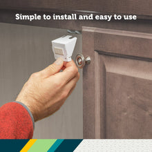 White cabinet latch being installed on a cabinet handle