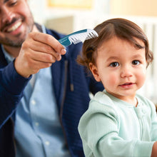 Baby grooming kit comb held over baby hair, teal handle