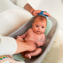 Teal baby brush grooming infant scalp in a bath