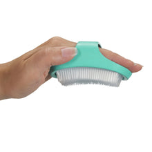 Hand holds aqua cradle cap brush with soft white bristle comb edge