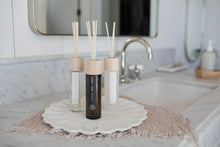 Reed diffuser set with amber, beige, and white bottles, and light wooden reed sticks
