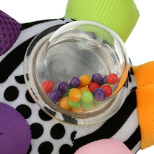 Close-up of clear rattle ring filled with colorful beads on patterned fabric ball