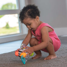 Plush zebra sensory rattle ball with teal ring handle, held by a child