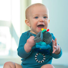 Baby holding grey whale plush sensory pull-down toy with black-white ring and blue layers