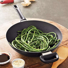 Nonstick wok with side handles, filled with sautéed green beans and herbs.