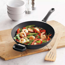 Nonstick wok with short handles, filled with shrimp and mixed vegetables.