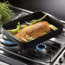 Roasting pan with salmon fillet and leek pieces on oven rack