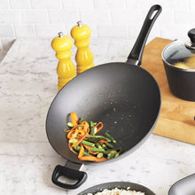 Nonstick wok with short side handles, filled with colorful stir-fry vegetables.
