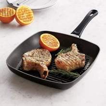 Square grill pan with ridged grill surface, black, holding seared pork with lemon