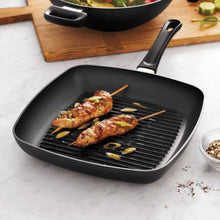 Square ridged grill pan with side handle, black, holding grilled chicken pieces