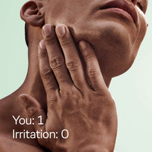 Man holding green handled disposable razor to face, grooming near cheek