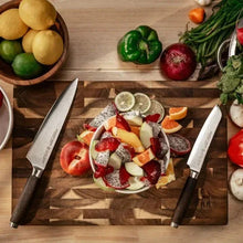 Chef knife on wooden cutting board with vegetables and citrus pieces