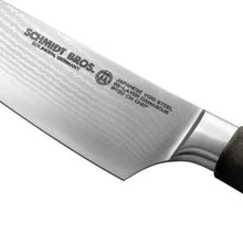 Chef knife blade close-up with patterned steel and branded markings