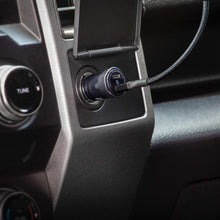 Black dual USB-C car charger plugged into dashboard power outlet with USB-C connector