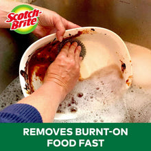 Stainless steel scrubber use: hand scrubbing a dirty pot in a sink.