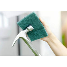 Green heavy-duty scour pad held near a sink faucet