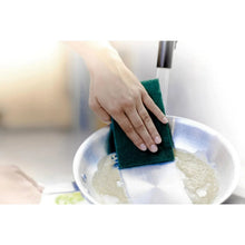 Green heavy-duty scour pad held above a bowl for cleaning